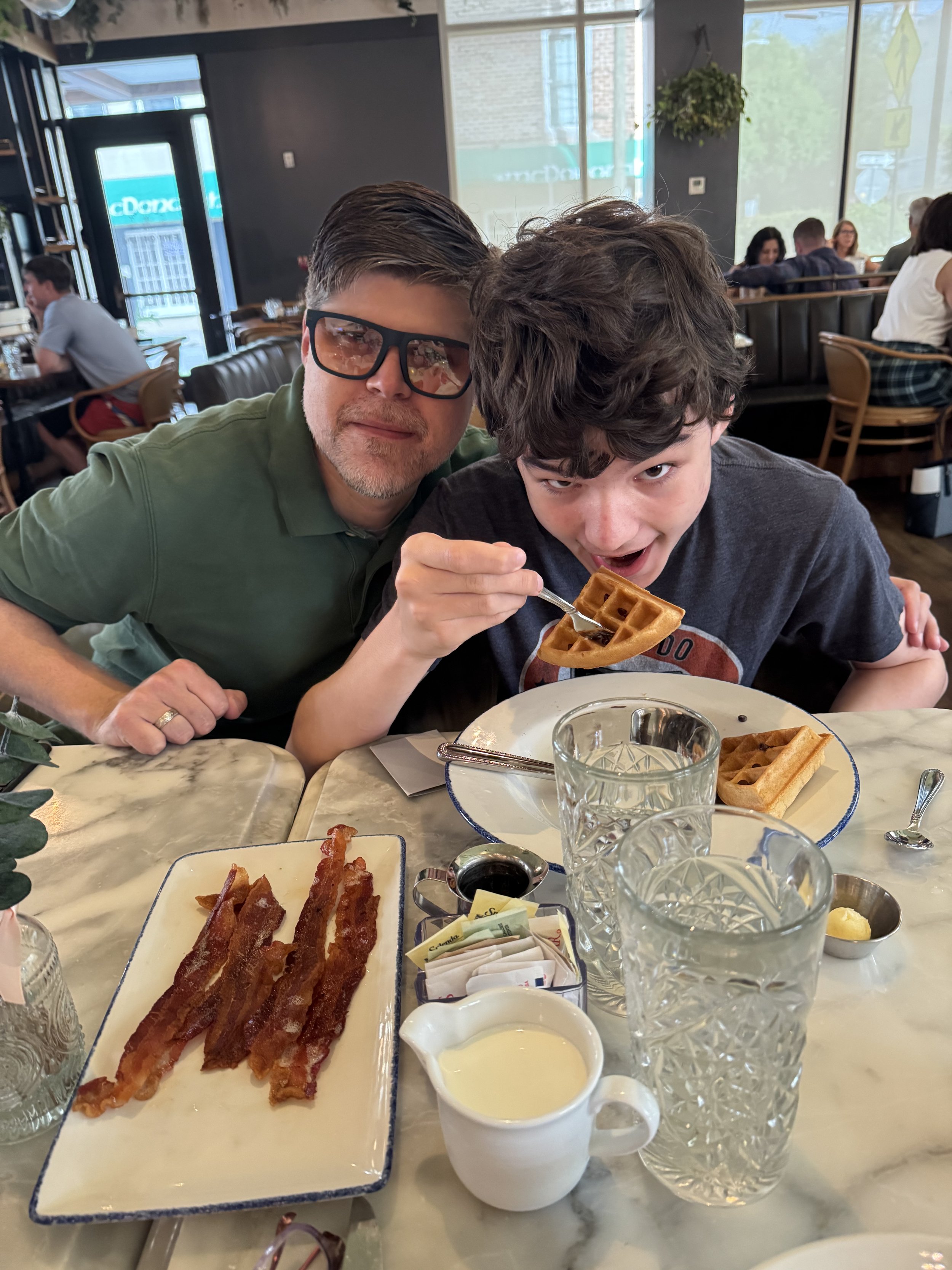 Man and boy enjoying waffles and bacon at breakfast