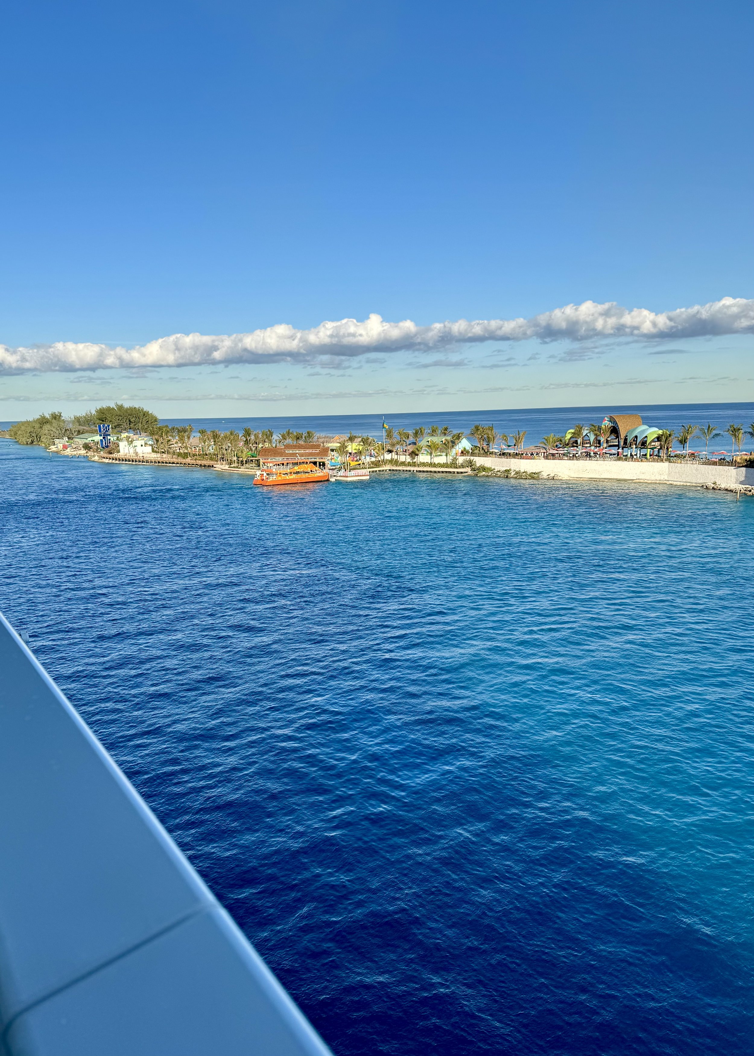 Cruise ship approaching tropical island port with orange ferry boat