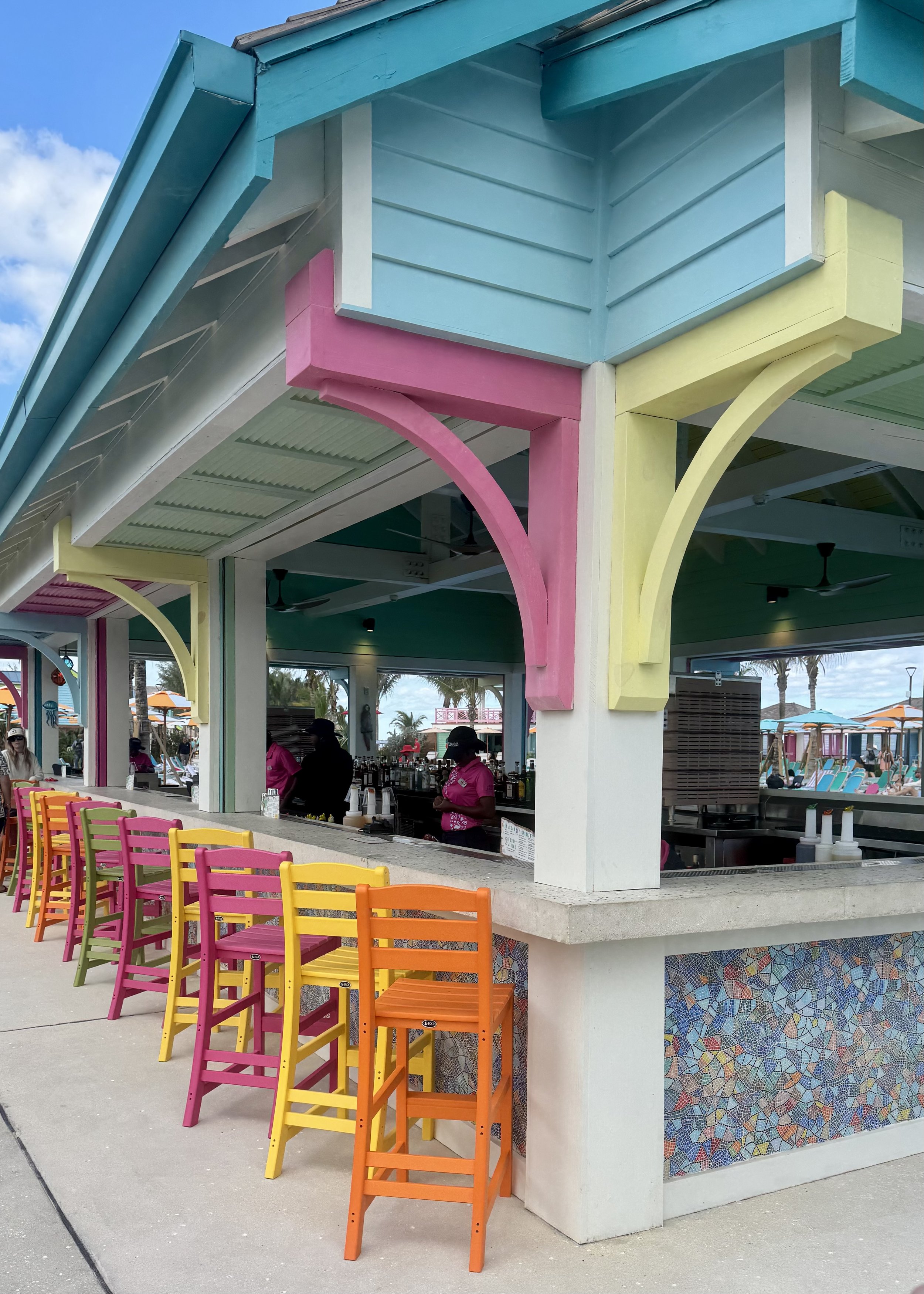 Colorful beachside bar with vibrant chairs and turquoise architectural details