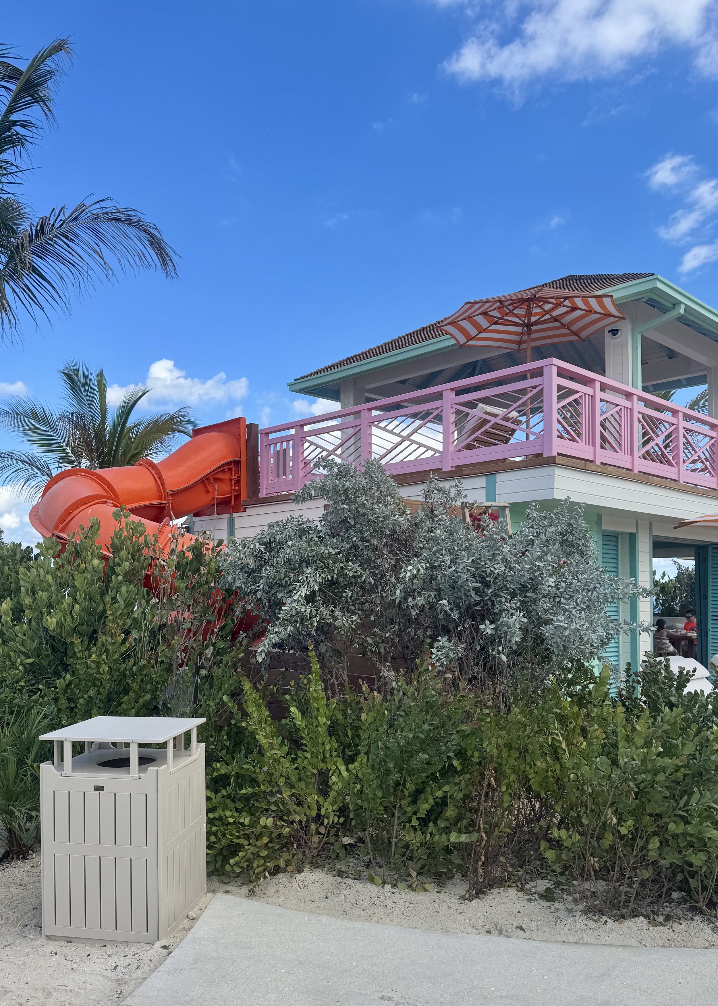 Colorful beachfront villa with red water slide and pink railings