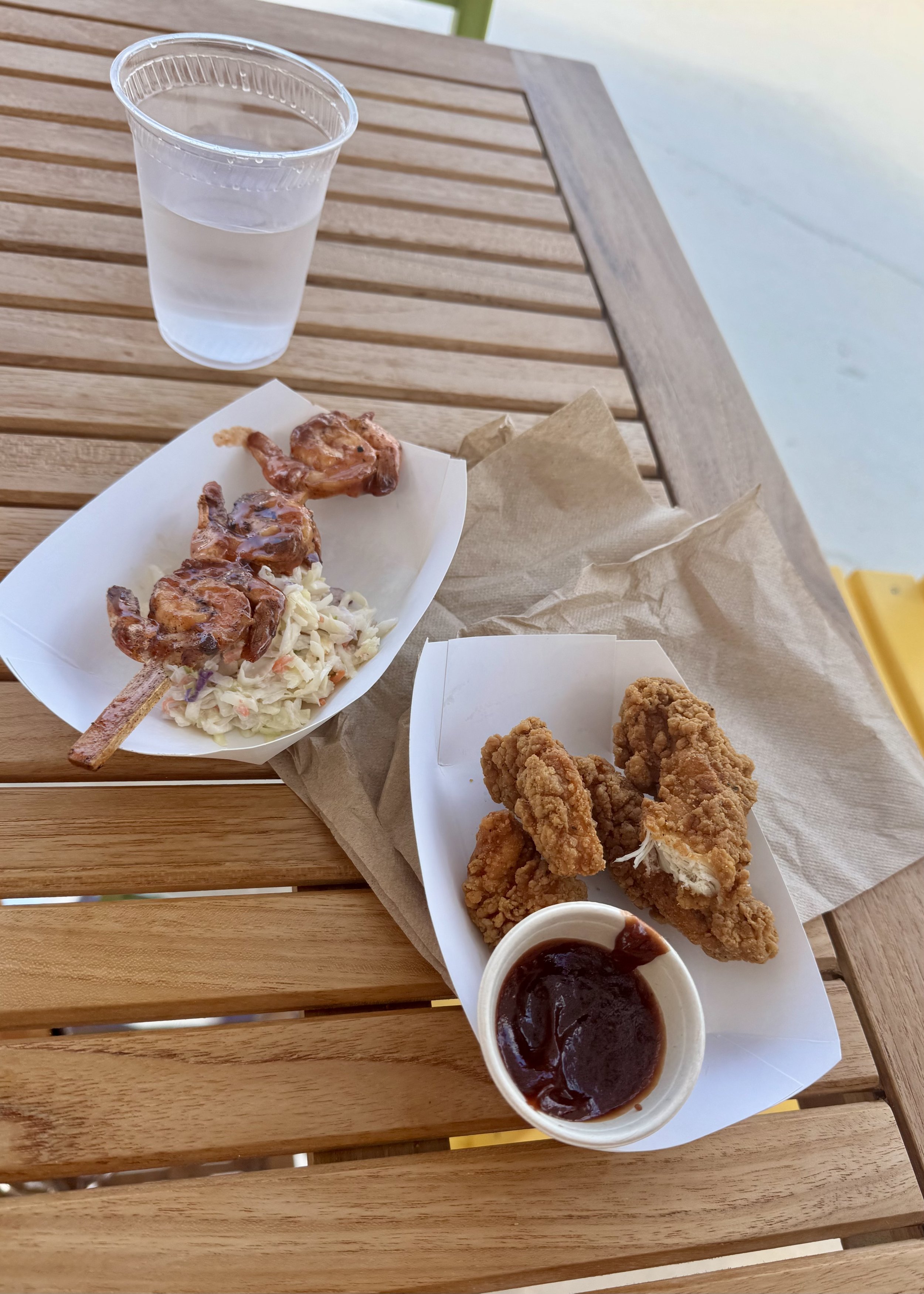 Outdoor deck lunch with fried chicken, shrimp skewers, coleslaw, water