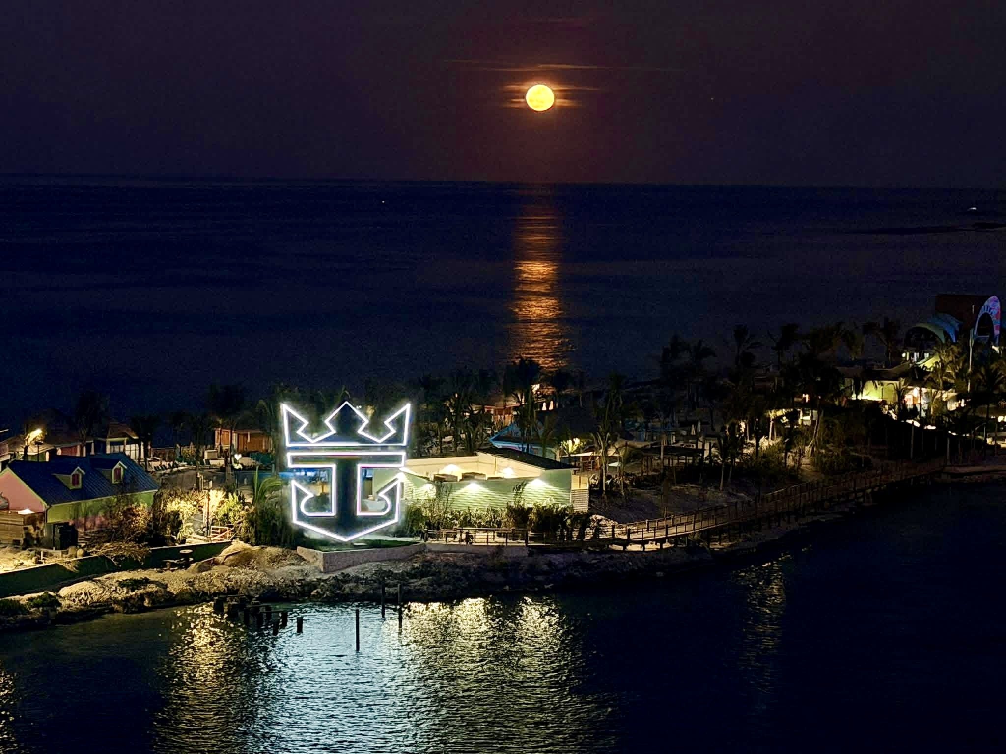Full moon rises over illuminated mini golf course at sea