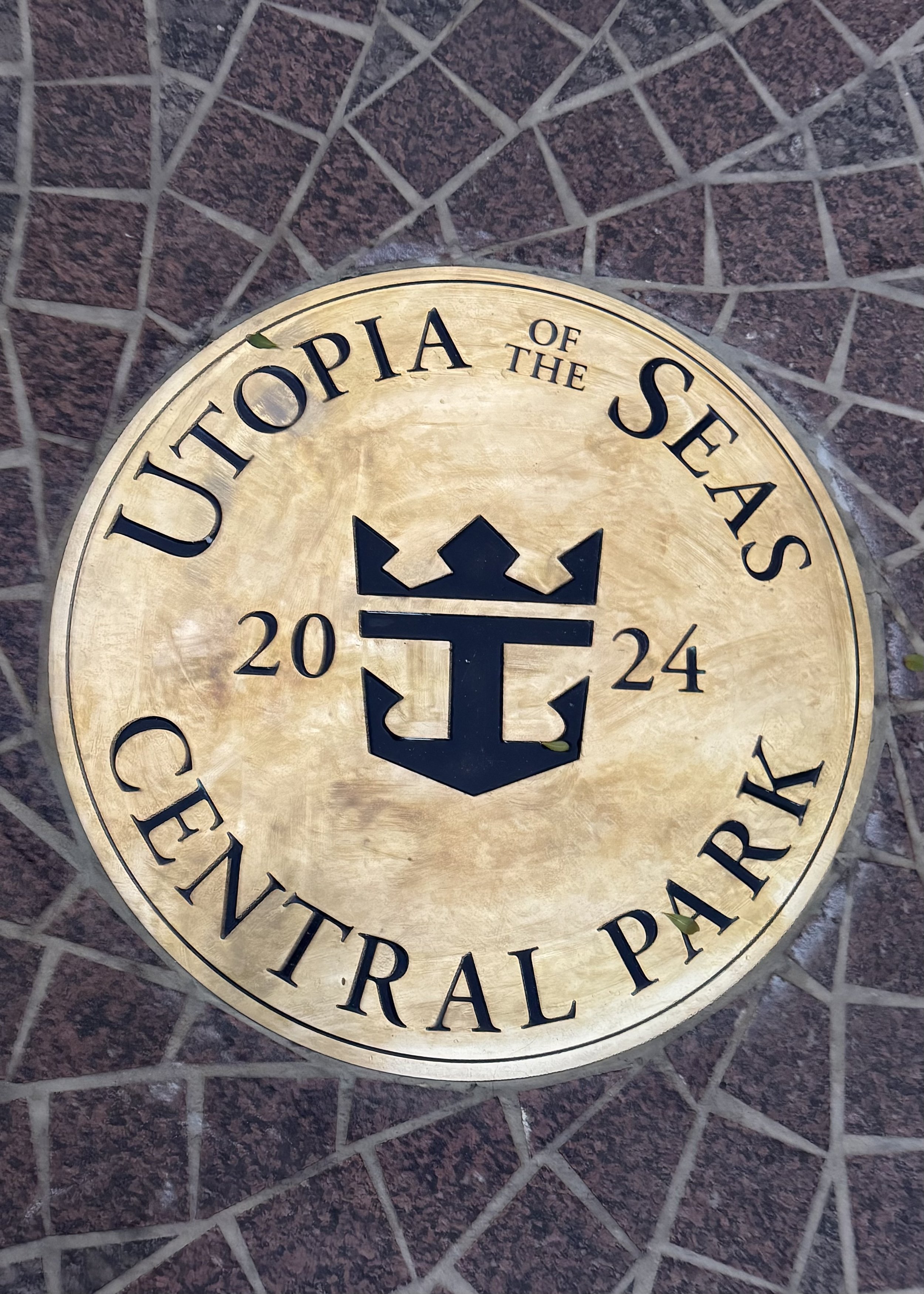 Utopia of the Seas Central Park plaque with anchor logo on brick background, 2024