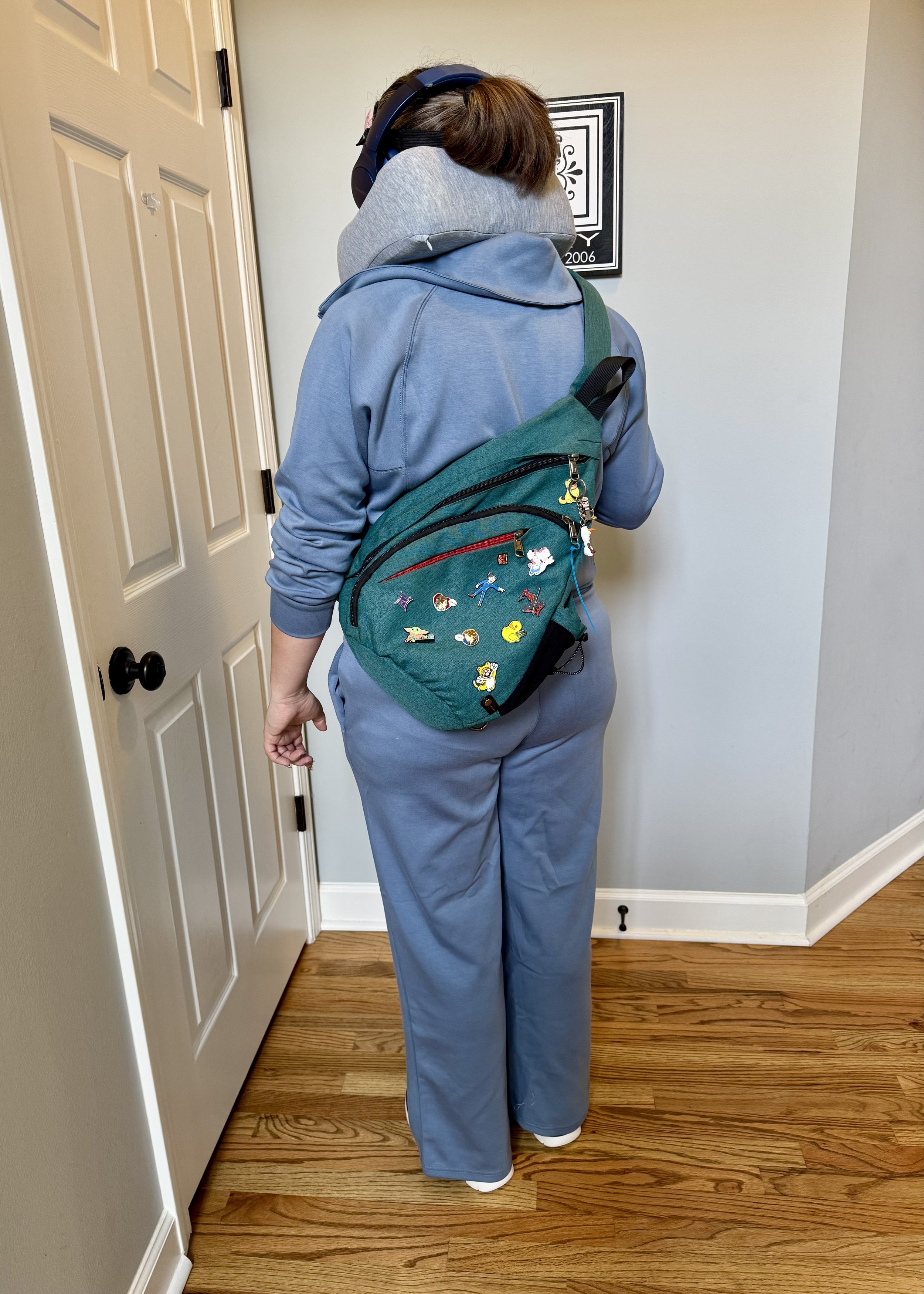 Person wearing green backpack with Disney pins in hallway