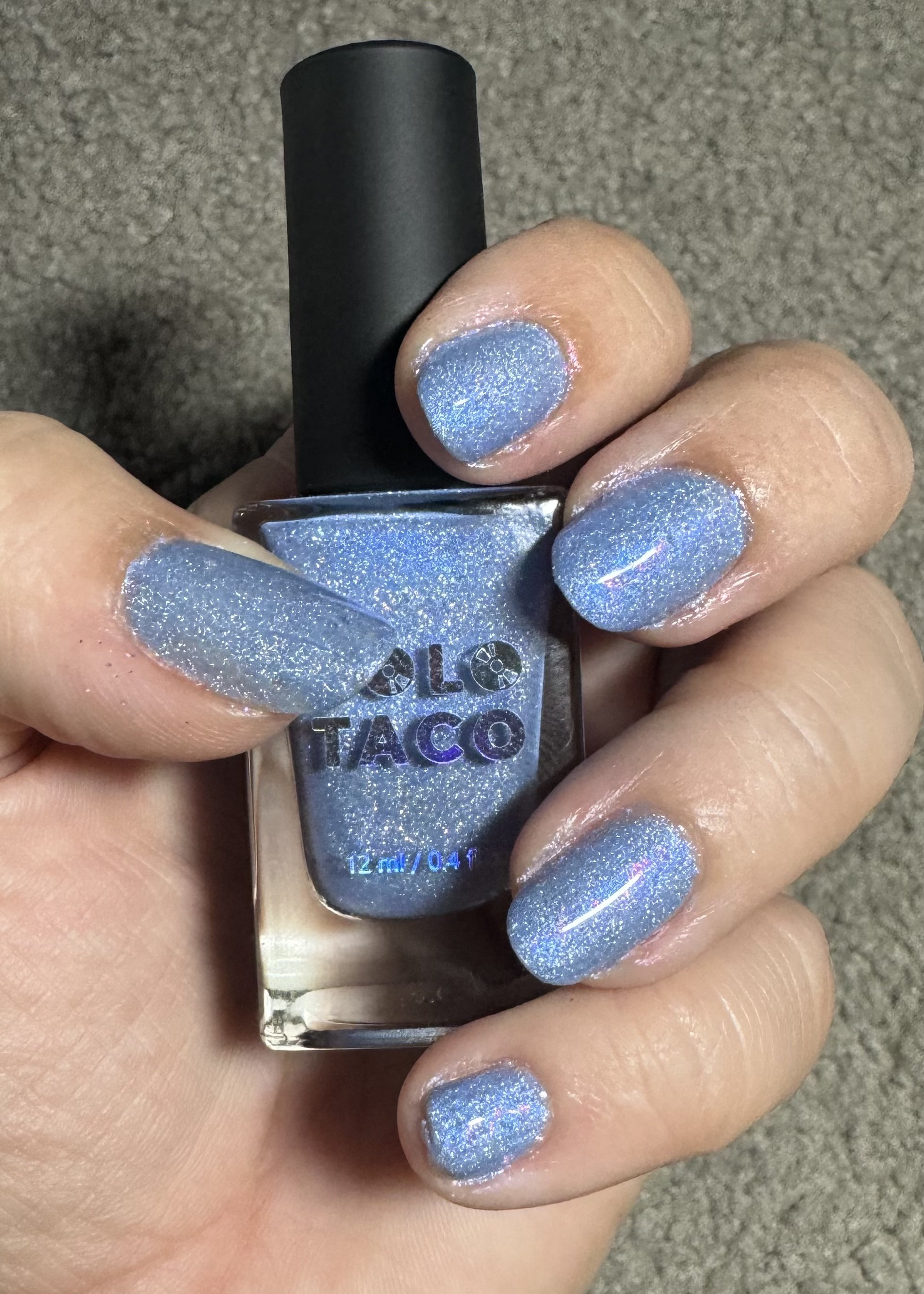 I can see this is a nail polish image, not a cruise travel blog image. The image shows a hand wearing blue glitter nail polish from El Taco brand.

If you meant to ask for alt text for this image as shown, here it is:

Blue glitter nail polish application by El Taco brand on manicured nails