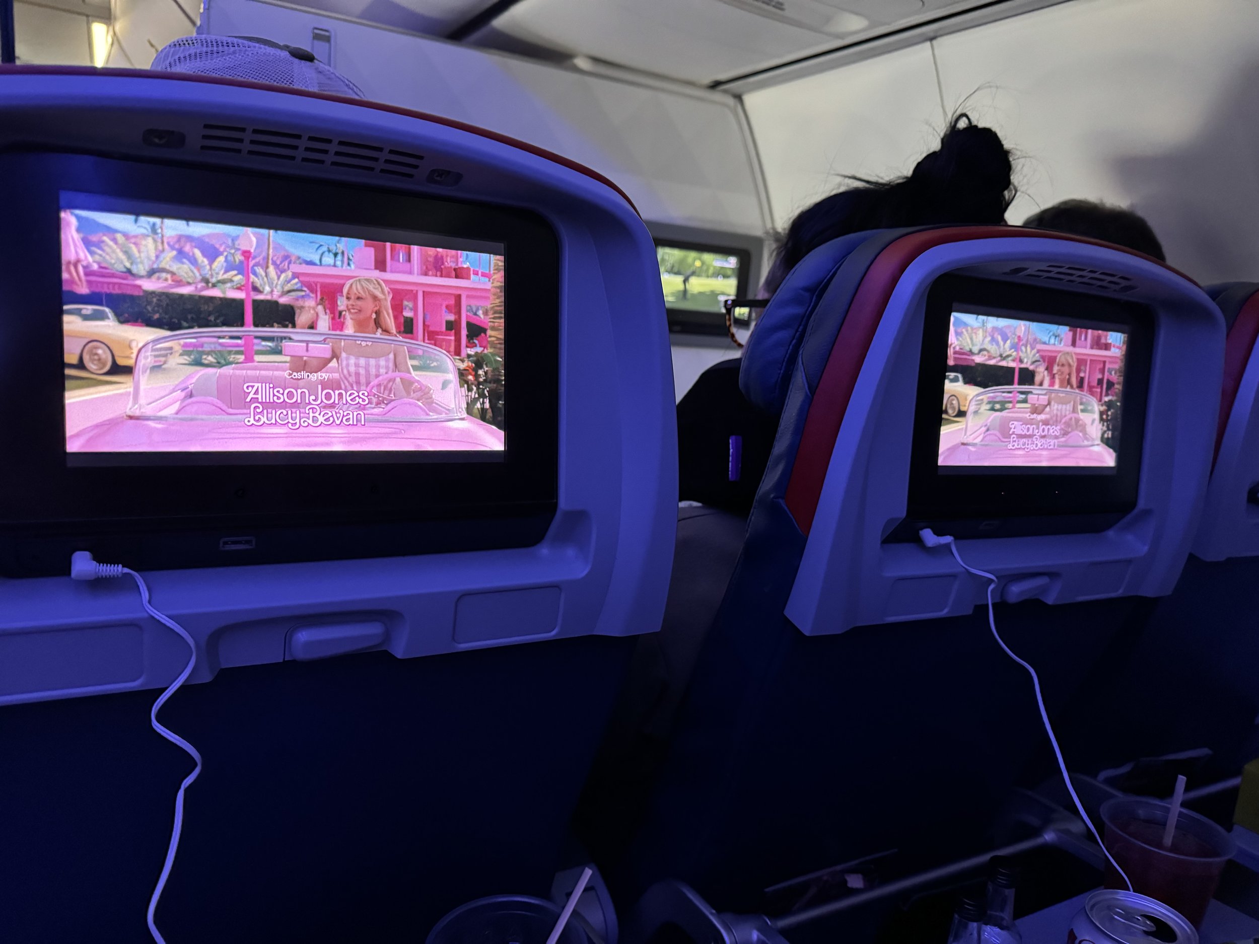Airplane cabin crew entertainment screens showing Barbie movie in flight