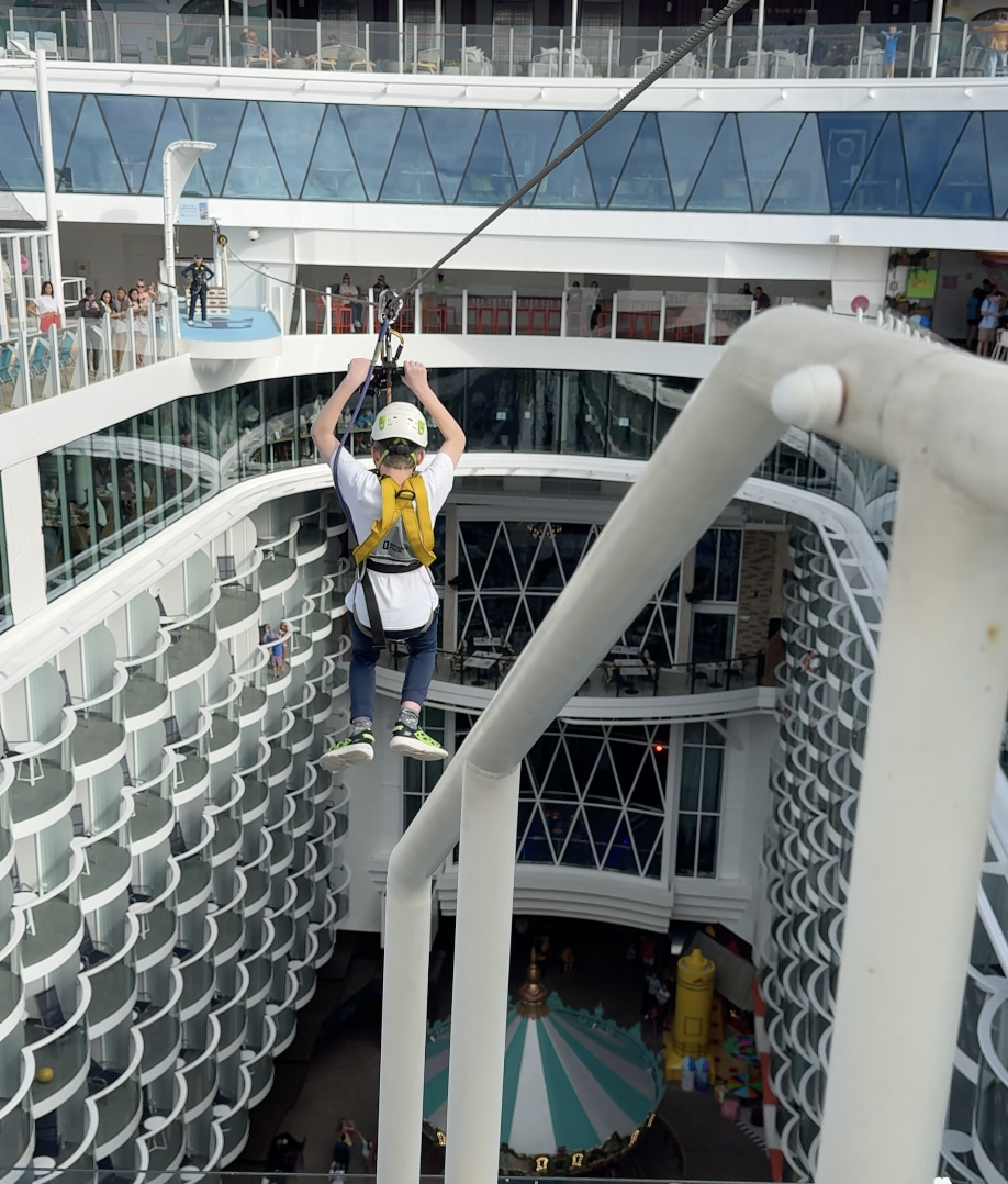 Person zip-lining across cruise ship atrium deck