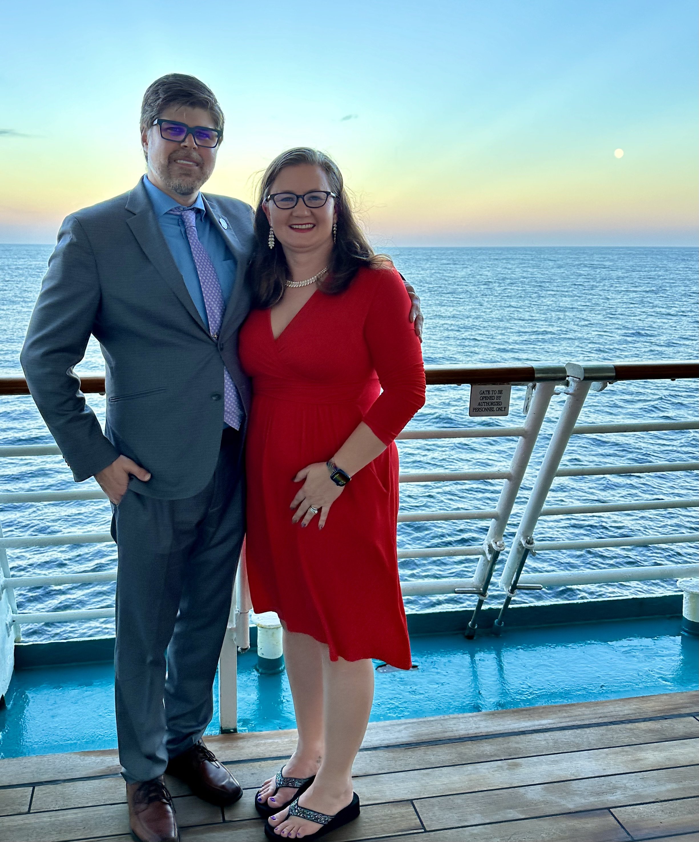 Couple in formal attire on cruise ship deck at sunset