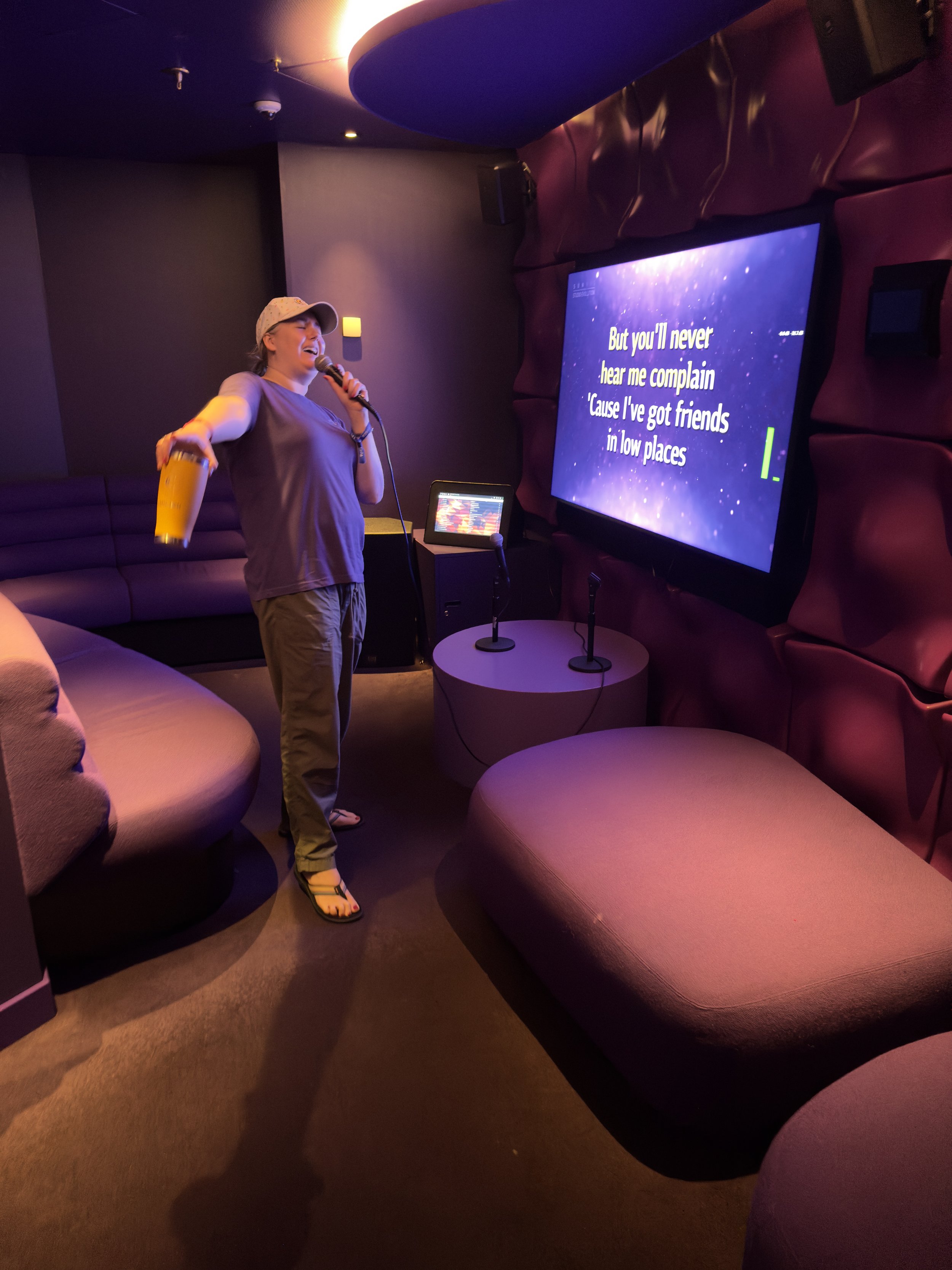 Person singing karaoke in cruise ship entertainment venue with lyrics displayed