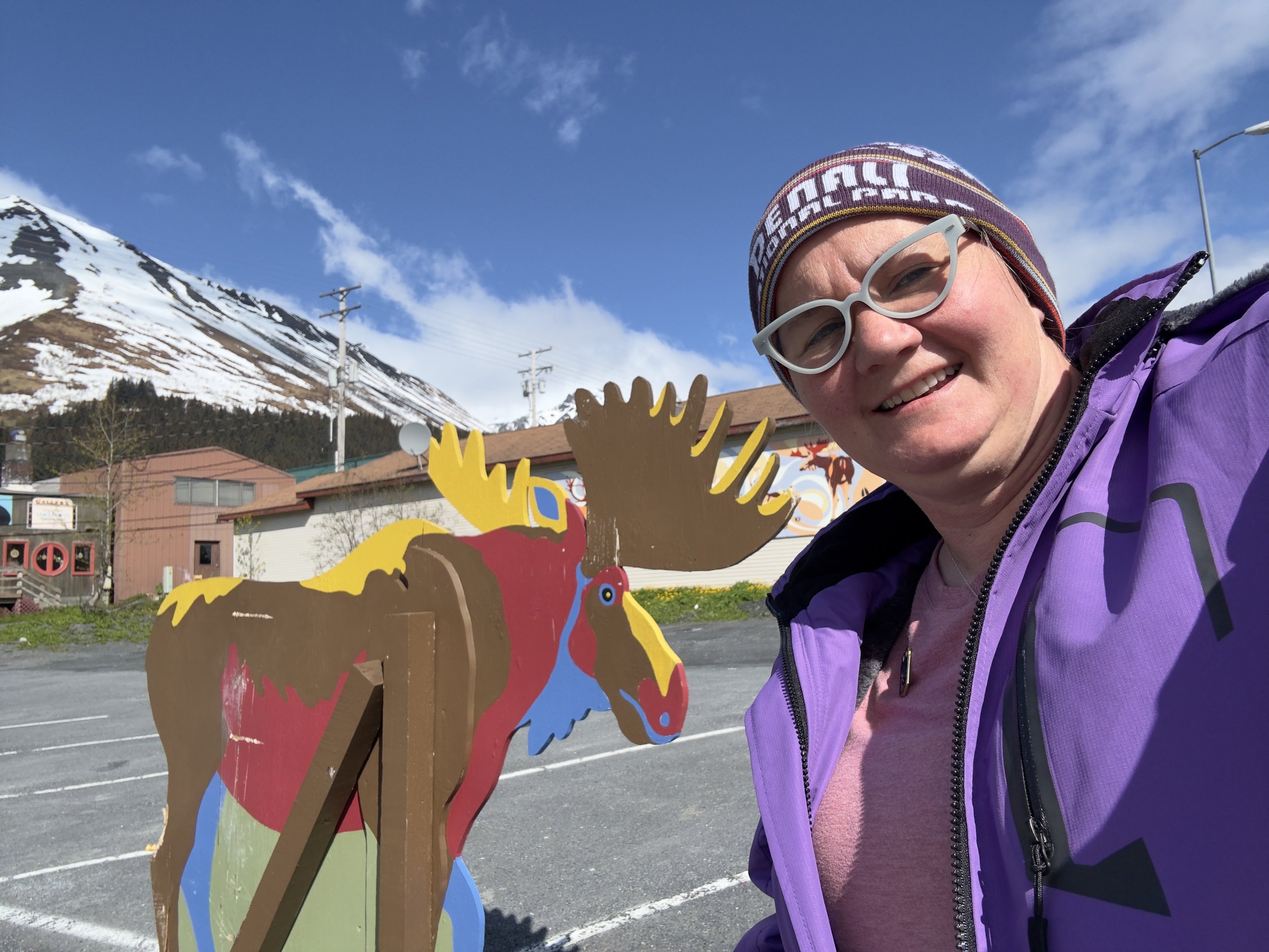 Woman poses with colorful moose statue in Alaska mountain town