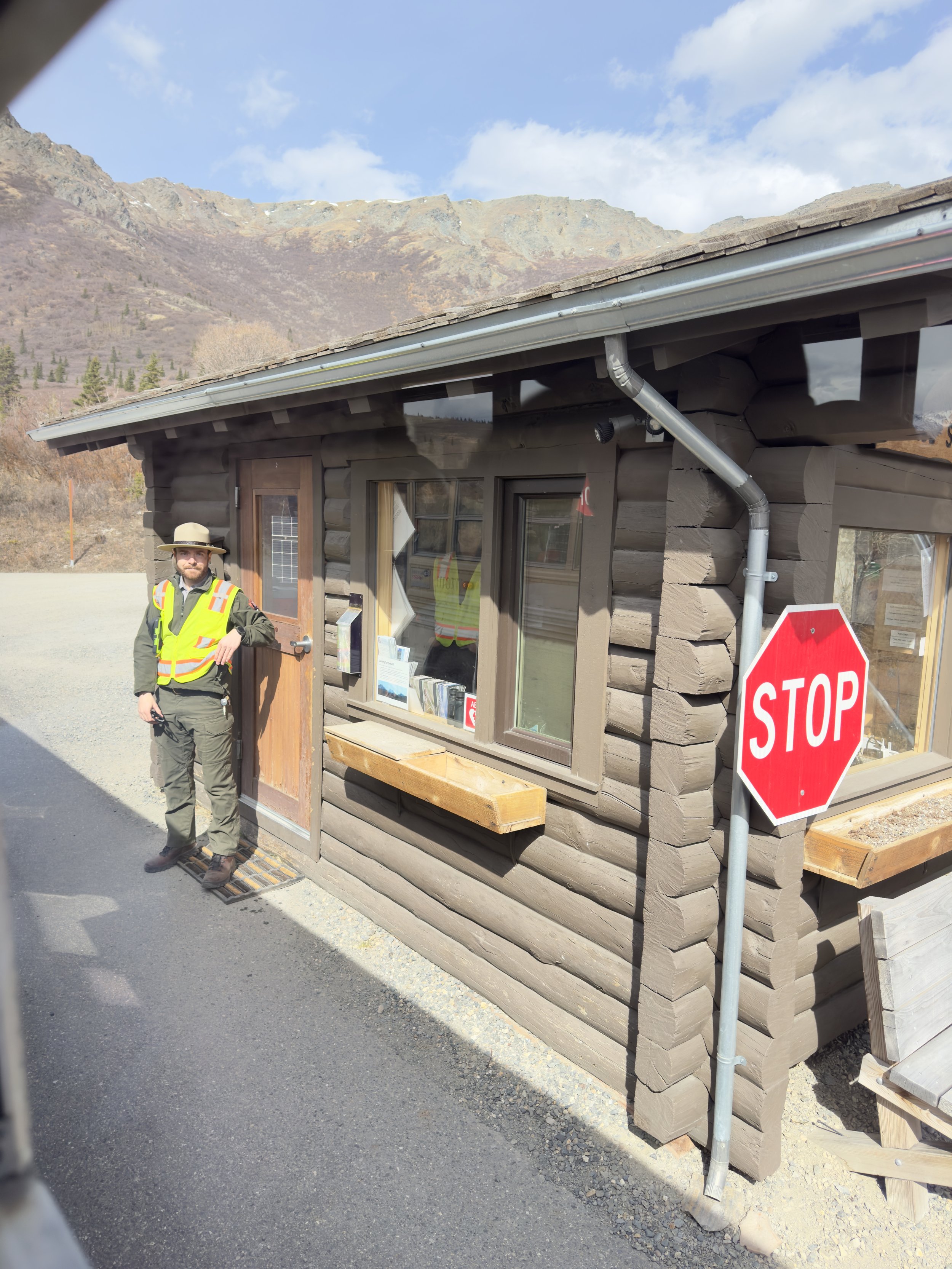 Park ranger at mountain entrance station with stop sign