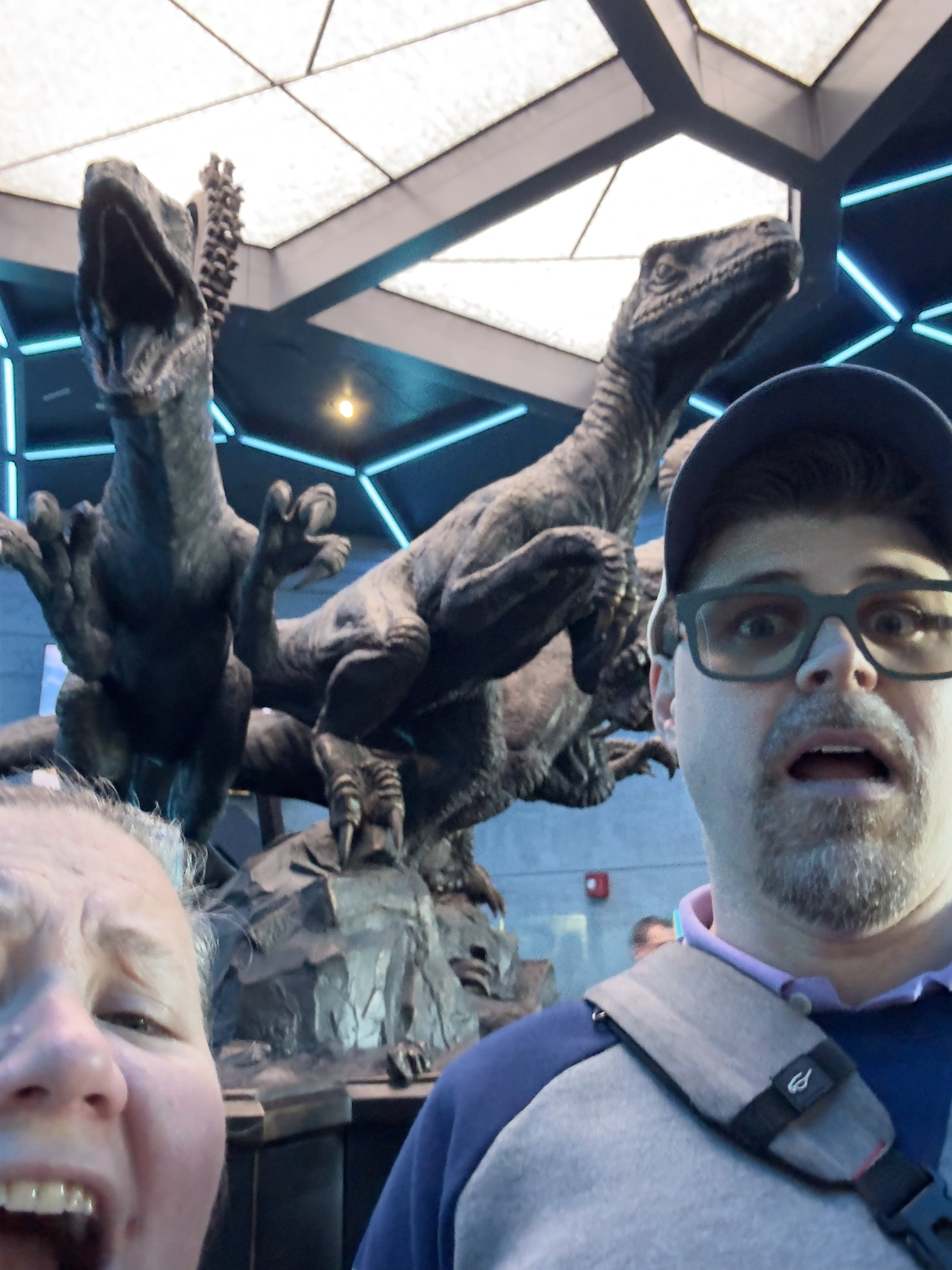Visitors pose with dinosaur statues in modern museum exhibit