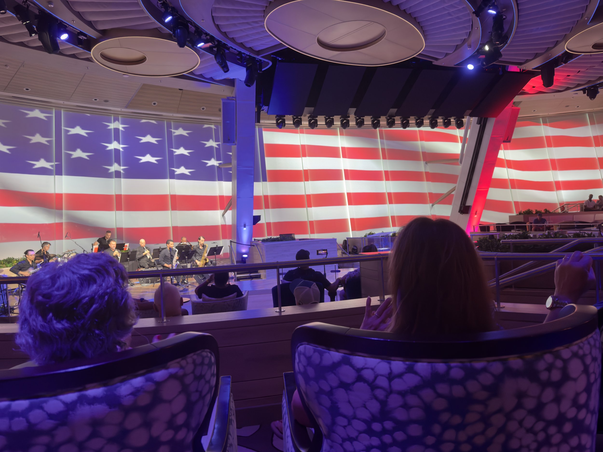 Orchestra performing on cruise ship theater stage with American flag backdrop