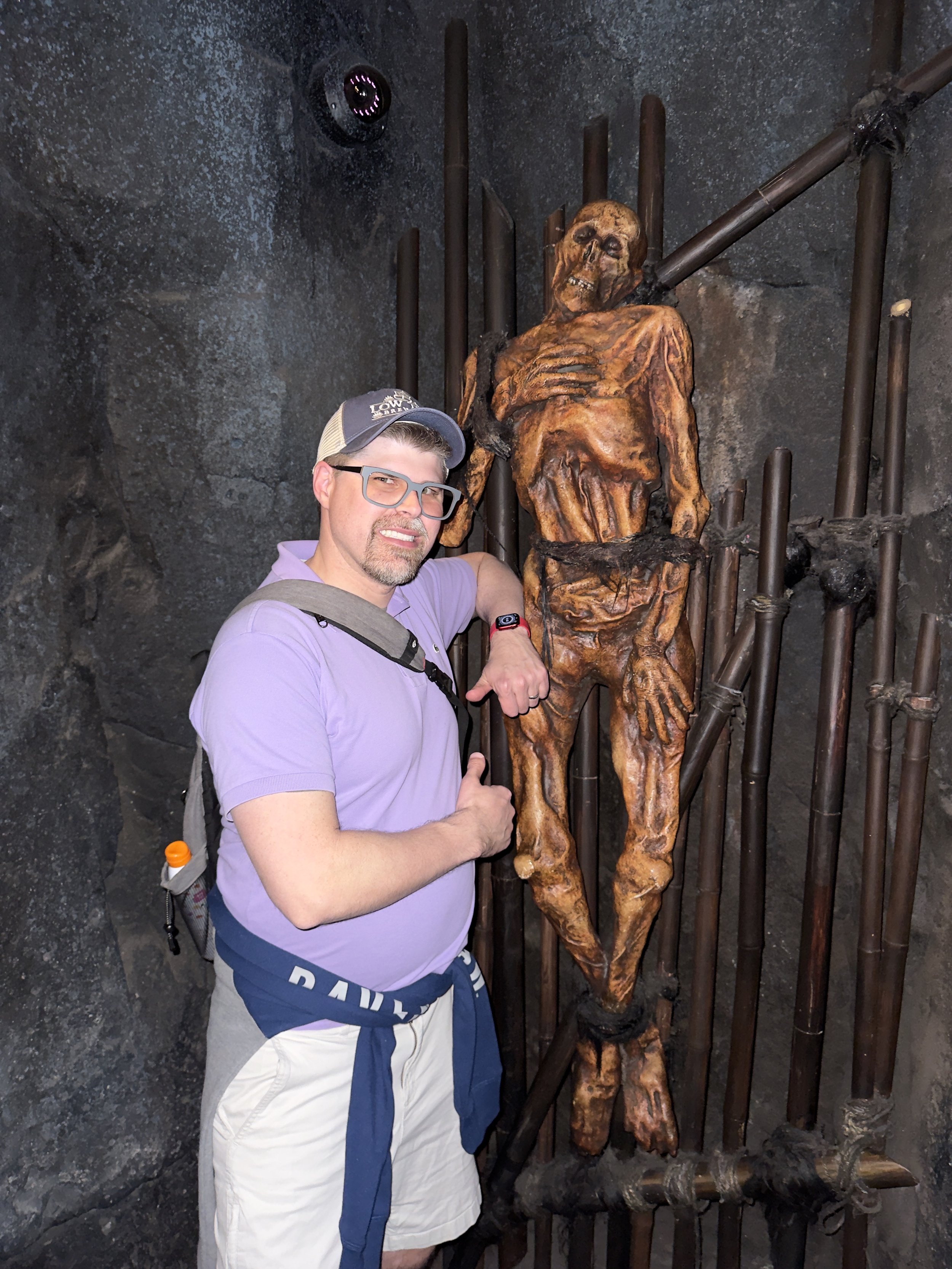 Man posing with bronze skeleton statue on cruise ship