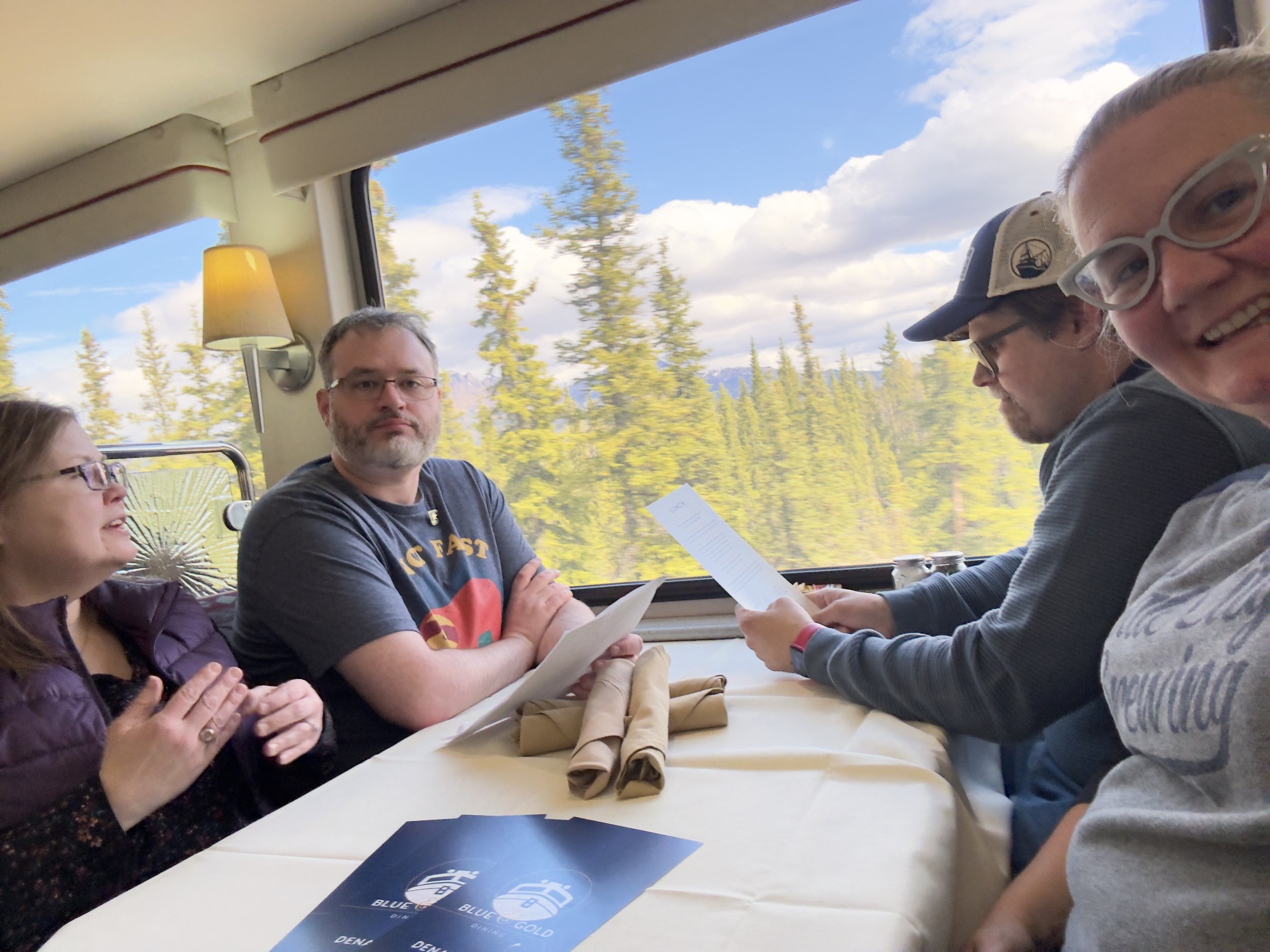 Group discussing maps inside cruise ship with forest views